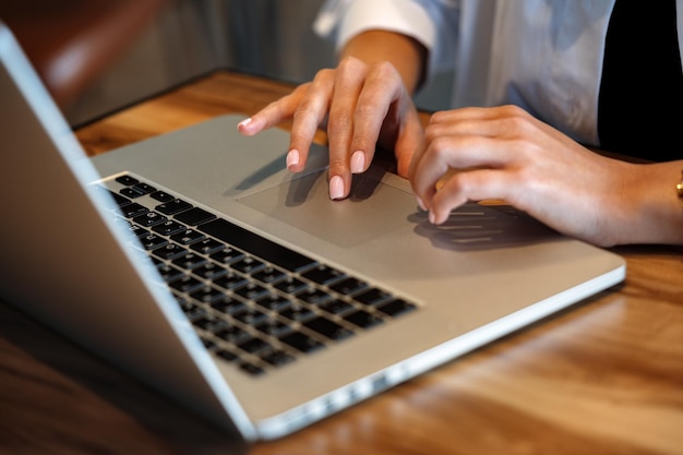 Primer plano de manos de mujer escribiendo en la computadora portátil en el café