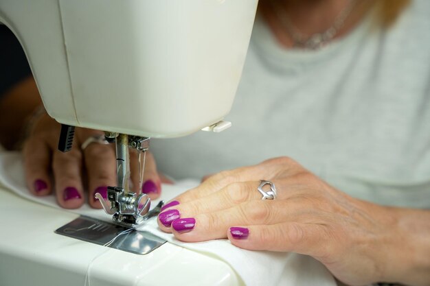 Primer plano de las manos de una mujer irreconocible cosiendo en su máquina de coser