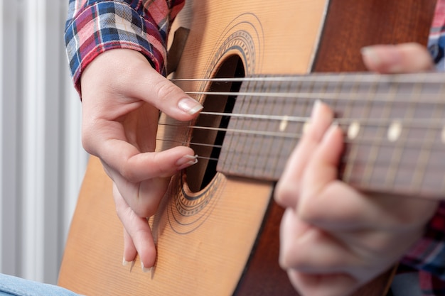 Primer plano de las manos de una mujer joven tocando la guitarra