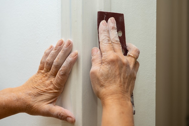 Foto un primer plano de las manos de la mujer está lijando la pared