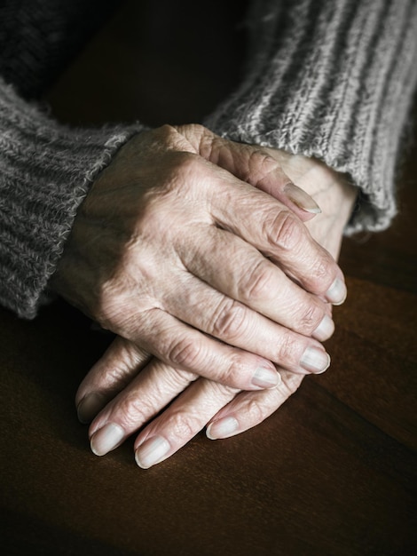 Primer plano de las manos de la mujer mayor en la mesa. fotografía dramática