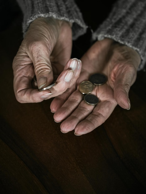 Primer plano de las manos de una mujer mayor con monedas de euro. Pensionista contando dinero en sus manos