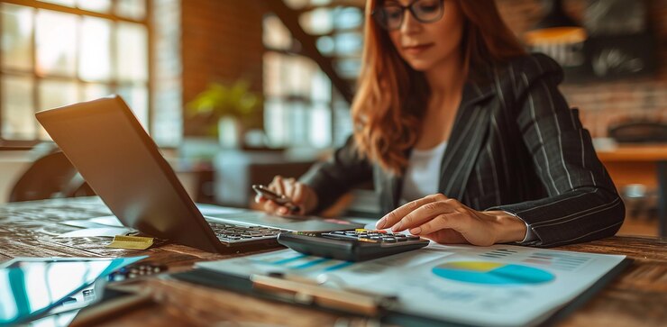 Primer plano de las manos de una mujer de negocios usando una calculadora y una computadora portátil en la oficina