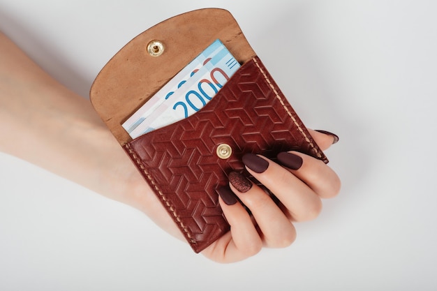 Primer plano de las manos de una mujer poniendo un billete de miles de rublos en un bolso.