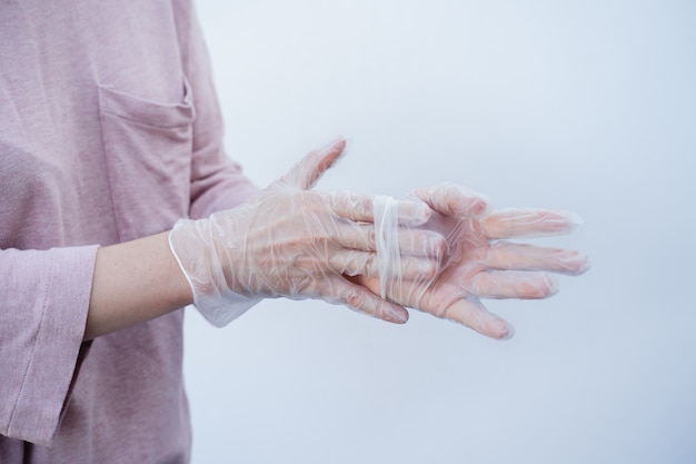 Foto primer plano de las manos de una mujer quitándose guantes de seguridad desechables durante la pandemia de coronavirus