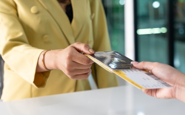 Primer plano de manos de mujeres jóvenes que muestran el pasaporte a la tarjeta de embarque en la terminal del aeropuerto