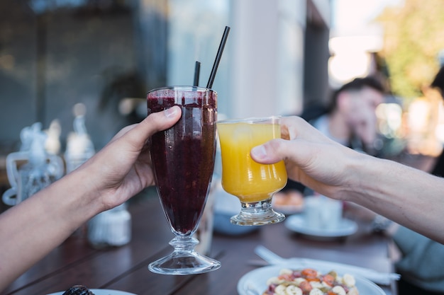 Primer plano de las manos de las mujeres con jugos de frutas.