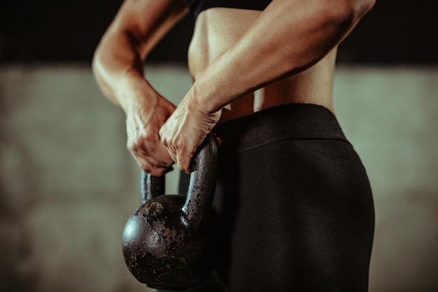 Primer plano de manos musculosas listas para hacer ejercicio con pesas rusas en el gimnasio.