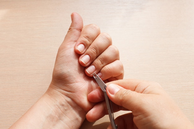 Primer plano de las manos, una niña haciéndose la manicura, cortaúñas.