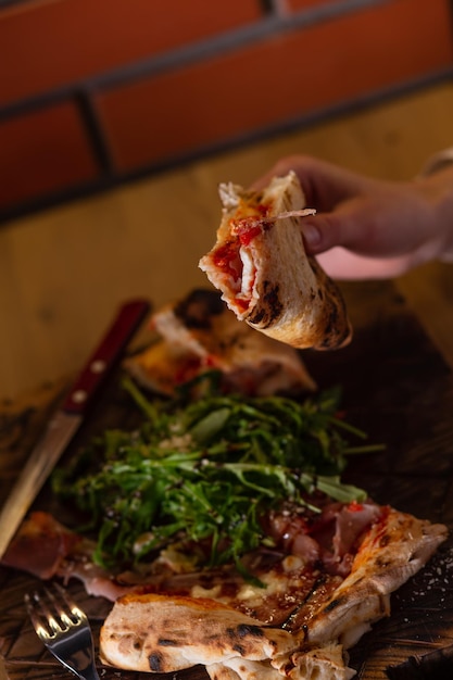 Primer plano de las manos de una niña que come bruschetta o pizza