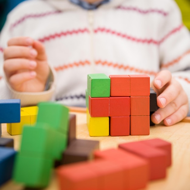 Primer plano de las manos de un niño armando un rompecabezas de coloridos cubos de madera Desarrollo temprano