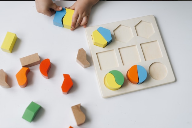 Primer plano de las manos del niño irreconocible jugando con coloridos juguetes de bloques de madera