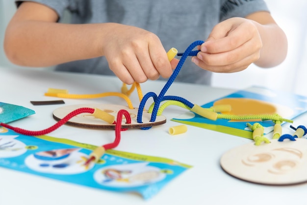 Foto primer plano de las manos del niño jugando con encaje o cuerda y pasta desarrollo de habilidades motoras finas educación temprana método montessori habilidades cognitivas