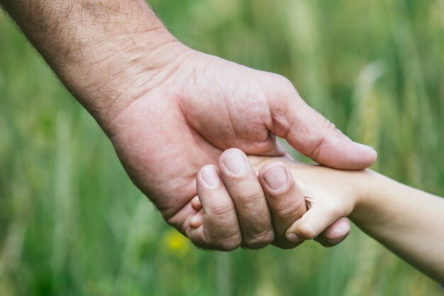 Foto primer plano de las manos de un niño pequeño y una persona mayor para permanecer juntos