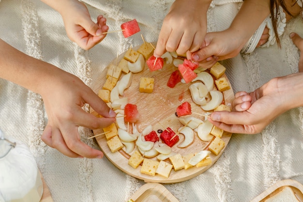 Primer plano de las manos de los niños disfrutando de postre de queso decorado con sandía