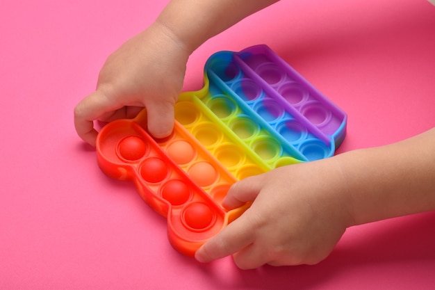 Un primer plano de las manos de los niños jugando con el popular juguete pop It fidget.
