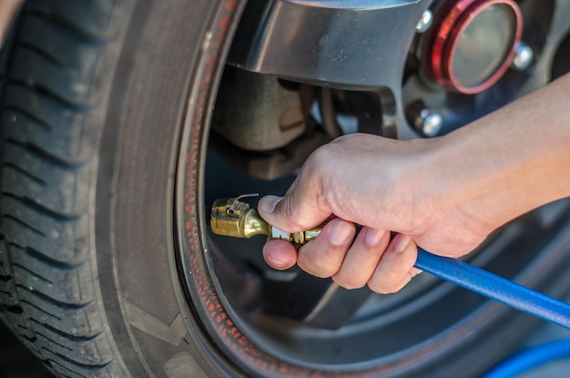 Foto primer plano de las manos de una persona inflando un neumático de coche