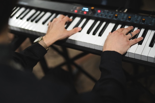 Foto primer plano de las manos de un pianista mientras toca el piano