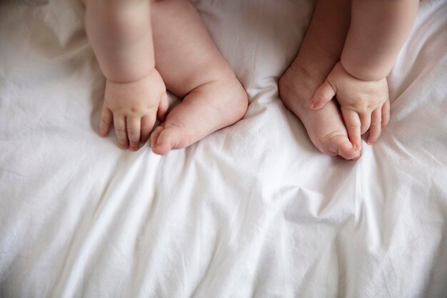 Primer plano de las manos y los pies de un bebé en una sábana blanca