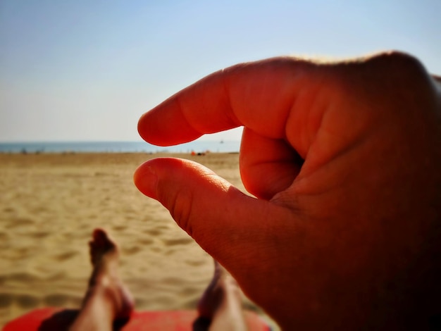 Foto primer plano de las manos en la playa contra un cielo despejado