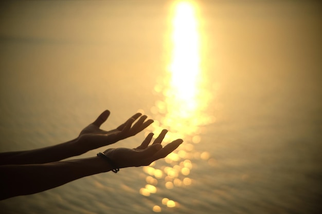 Primer plano de las manos sobre el mar durante la puesta de sol