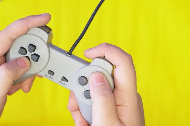Primer plano de manos sosteniendo el controlador de juego contra un fondo amarillo