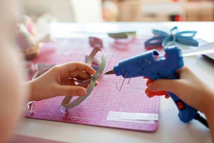 Foto primer plano de manos sosteniendo una pistola de pegamento en la mesa