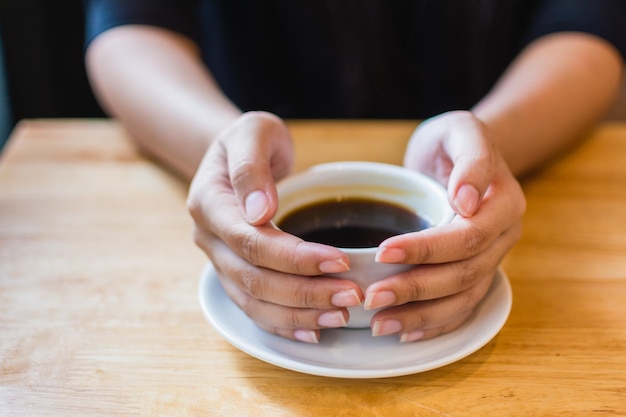 Primer plano de las manos sosteniendo la taza de café