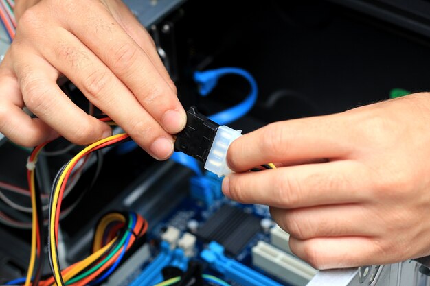 Primer plano de las manos de un técnico cableando una placa base de computadora