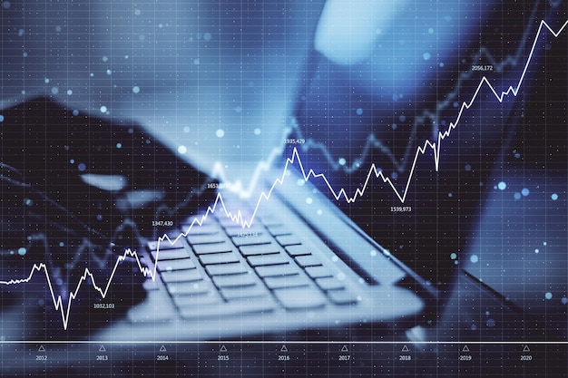 Primer plano de las manos usando una computadora portátil con gráfico de forex Concepto de red y comercio Doble exposición