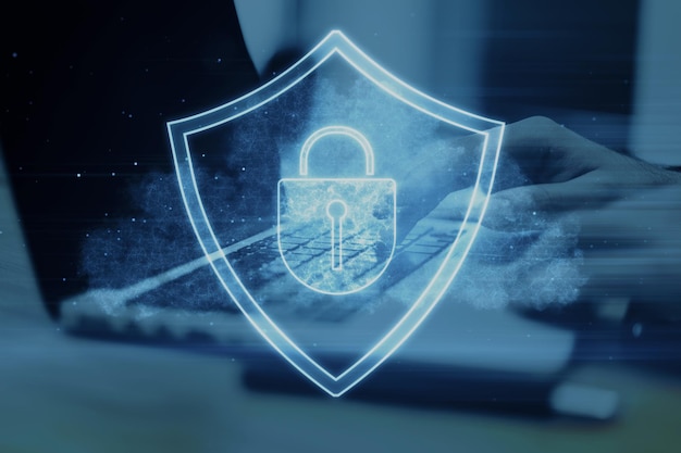 Primer plano de las manos usando una computadora portátil con un holograma de escudo brillante en la pantalla Fondo de escritorio borroso Protección segura y concepto de seguridad web