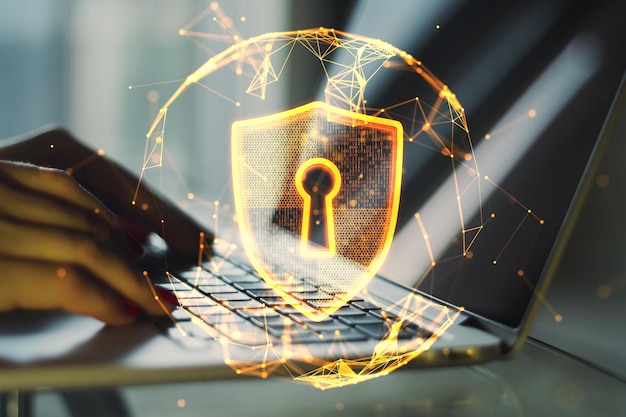 Primer plano de las manos usando el teclado de una computadora portátil con una esfera poligonal brillante abstracta con un escudo de candado digital brillante sobre fondo borroso Protección de seguridad y concepto de tecnología Doble exposición