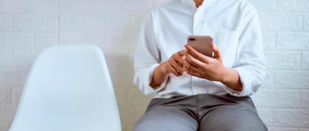 Primer plano de las manos usando el teléfono inteligente en la silla y escribiendo mensajes a sus amigos.