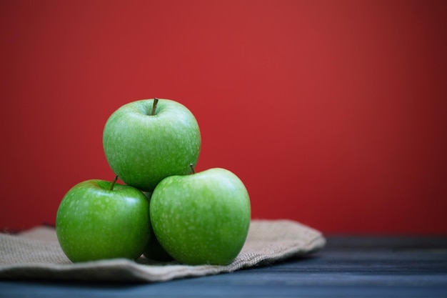 Primer plano de manzanas en la mesa contra un fondo rojo