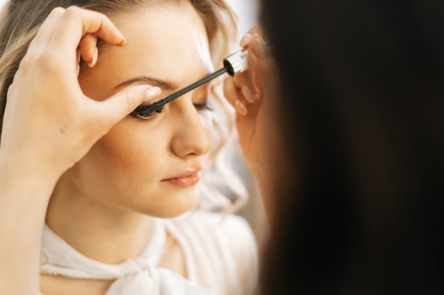 Primer plano de una maquilladora profesional poniendo sombras en los párpados en un salón de belleza