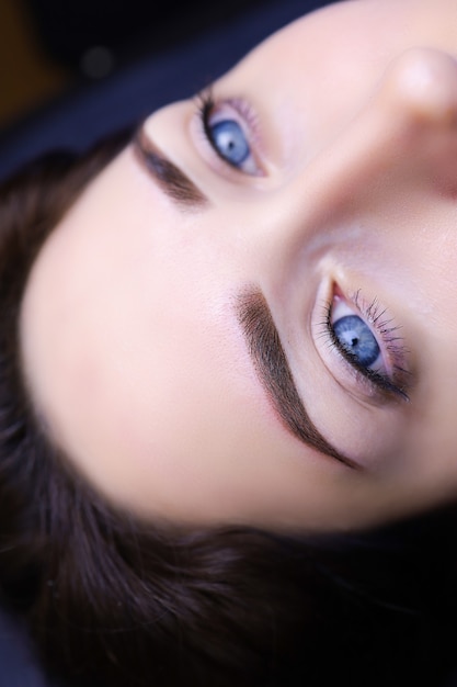 Primer plano de maquillaje de cejas permanente. chica modelo con ojos azules