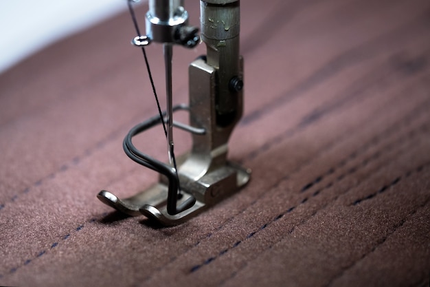 Primer plano de la máquina de coser eléctrica doméstica y prenda de vestir.