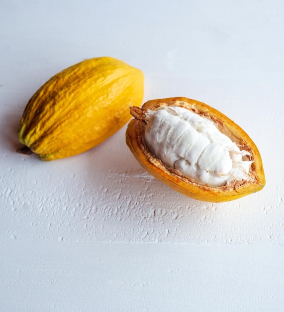 Primer plano de mazorcas de cacao frescas y maduras, la mitad de la fruta de cacao cortada, revelando el blanco
