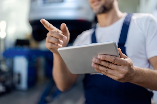 Foto primer plano de un mecánico usando el panel táctil en el taller de reparación de automóviles