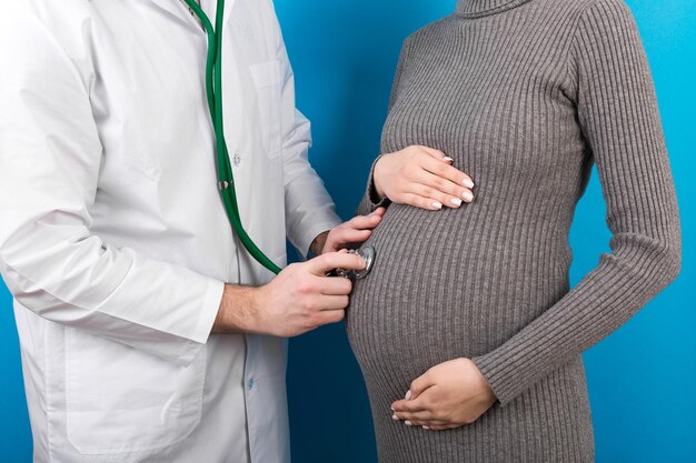 Primer plano de un médico examinando a una mujer embarazada en un fondo colorido