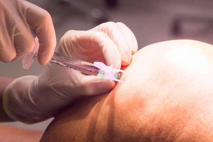 Foto primer plano de un médico inyectando a un paciente de rodillas