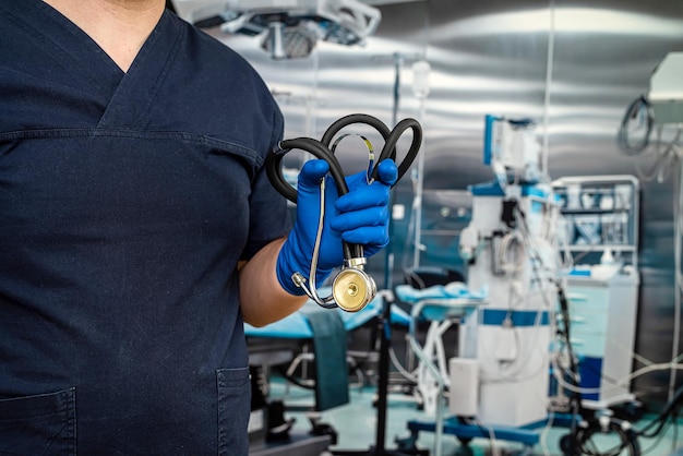 Primer plano de un médico masculino que usa estetoscopio y guantes de uniforme azul oscuro en la sala de emergencias Trabajadores de la salud contra el brote de coronavirus