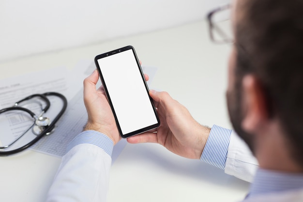 Foto primer plano de un médico masculino utilizando un teléfono móvil con pantalla en blanco