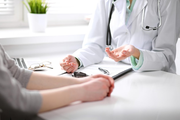 Primer plano del médico y el paciente sentados en el escritorio cerca de la ventana del hospital