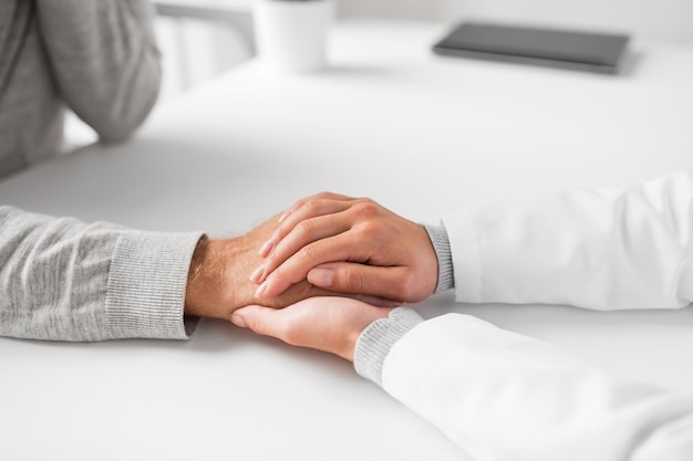 Foto primer plano de un médico sosteniendo la mano de un paciente mayor