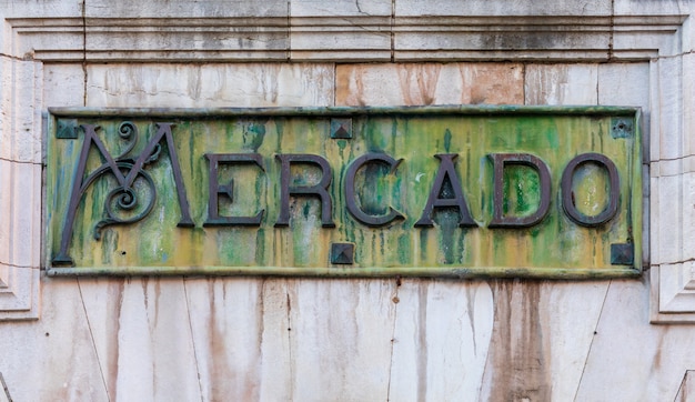 Primer plano del Mercado de Abastos, en español. En bronce oxidado, con tonos verdes y ocres.