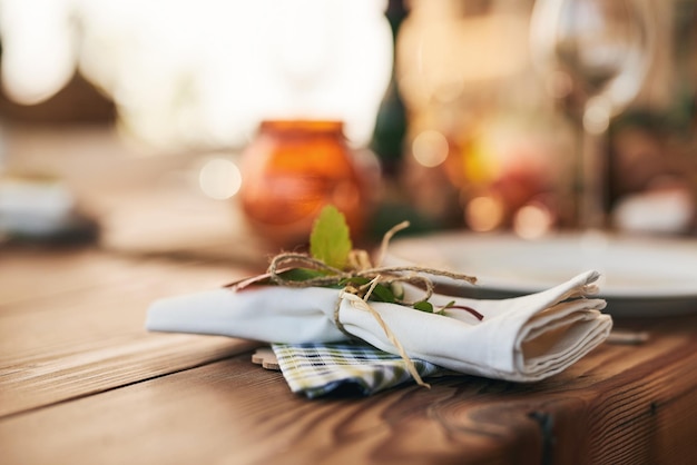 Primer plano de la mesa y el ambiente con una servilleta y corbatas para celebrar con una comida o comida festiva Mesa de comedor y plato de vacaciones para una cena o almuerzo con un fondo bokeh vacío sin nadie