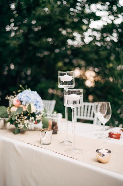 Primer plano de una mesa de cena de boda en la recepción velas flotan en el agua en candelabros de cristal alto