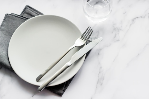 Primer plano de la mesa con cubiertos de plata de plato gris vacío en una servilleta de lino Decoración de mesa