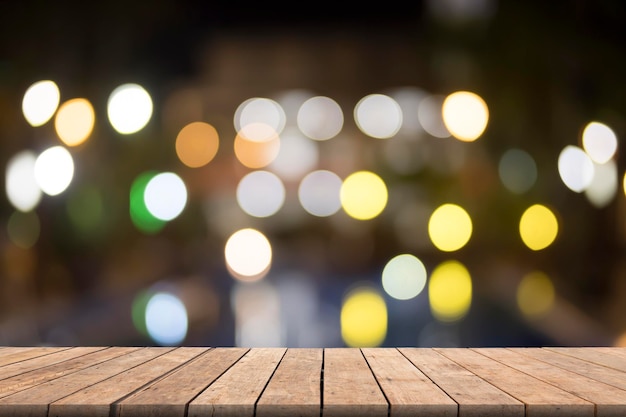 Primer plano de una mesa de madera contra luces iluminadas
